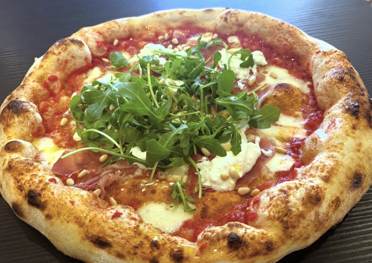 Pizza napolitaine au cornicione doré sortant du four à bois